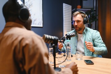 Man recording podcast using high tech microphones to interview guest, ensuring flawless video and...