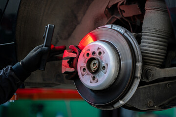 Serviceman checks the brake discs of a car