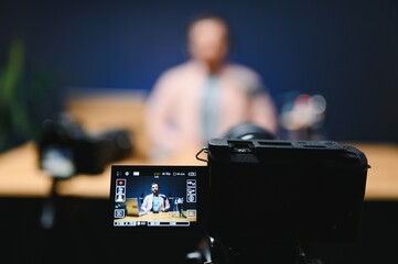 Man podcaster influencer blogger smiling while broadcasting his live audio podcast in studio using...
