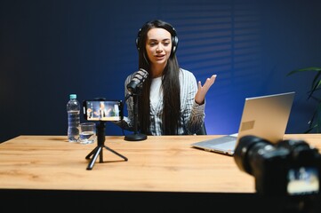 Positive female vlogger recording a video on camera sitting at desk