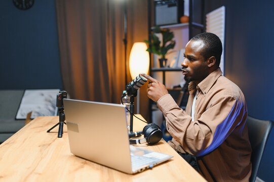 Young African American male vlogger influencer in headphones record video blog on smartphone