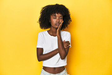 Teen girl in classic white T-shirt, yellow studio backdrop who is bored, fatigued and need a relax...