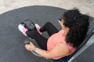 Senior woman exercising arms on fitness machine outdoors in park