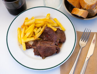 Spanish Secreto de cerdo - fried pork in red, served with french fries