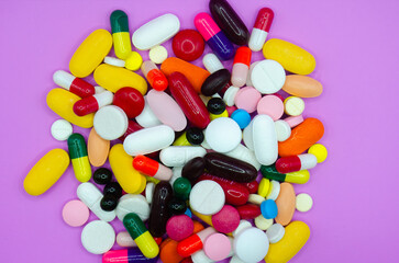 Assorted Colorful Pills and Capsules on Purple Background – Pharmaceutical Medication Concept
