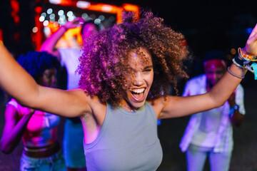 Enthusiastic young woman dancing with friends at a music festival