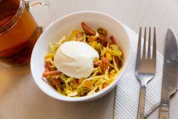 Salad with smoked sausage, green peas, grated yolk and sour cream. Russian cuisine
