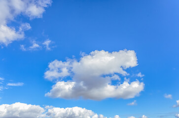The sky is endless and deep blue, with cotton-like clouds scattered. Some clouds are light and airy, while others are dense, making the scene visually rich.