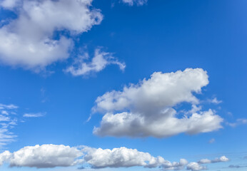 A vast blue sky with scattered clouds forms a dreamy, calm scene. The clouds vary in size and shape, adding depth and texture to the beautiful landscape.