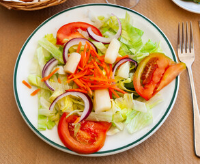 Appetizing salad of fresh greens, tomatoes, onion, grated carrot and marinated white asparagus