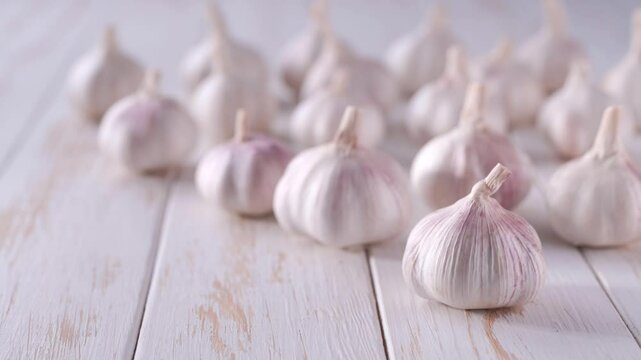 Raw whole garlic on a wooden table . 
fresh garlic on a white wooden table.