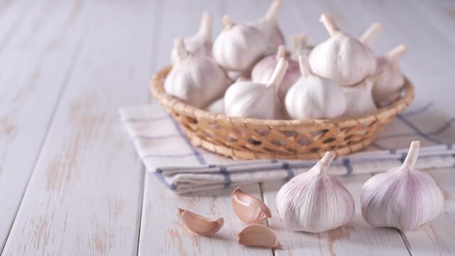 garlic bulbs in a basket on a white wooden table. whole garlic bulbs in a basket on a kitchen wooden table.
