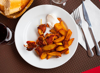 Delicious fried chicken kebab with potato pieces and sauce served on plate