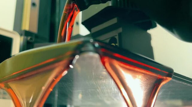 Pouring transparent red photopolymer or photosensitive resin into a modern SLA 3D printer before the printing, close-up