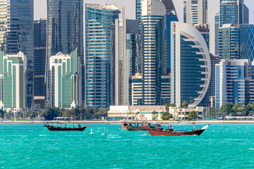 Doha modern business downtown center skyscrapers shoreline with small traditional arab dhow...