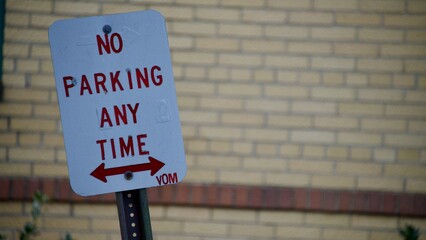 no parking sign with a yellow brick building 