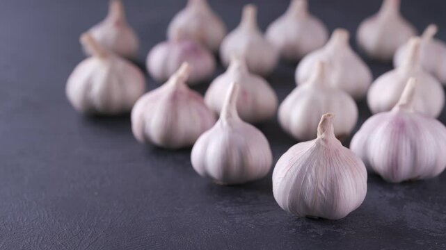 Garlic bulbs and garlic cloves on a black stone table. Garlic on a black table. 
