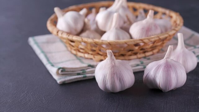 garlic bulbs in a basket on a black stone table.
 whole garlic bulbs in a basket on a black table.