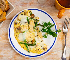 Scrambled eggs with vegetables, asparagus, chicken and mushrooms, garnished with parsley