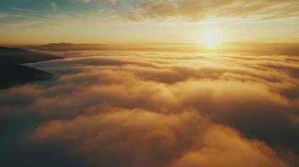 Obraz premium Above the clouds at sunrise, a high-altitude mist blankets the landscape, with rolling fog and a golden horizon unfolding in breathtaking cinematic beauty.