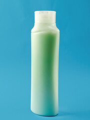 A bottle of ocean earth green soap with a white cap. The bottle is tall and slender. The blue liquid inside the bottle is clear and colorless. Ocean blue background. Health and beauty product.