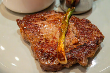 Large beef rib eye steak grilled on gas stove in German restaurant