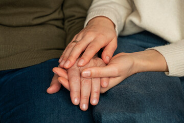 A daughter and mother reunite after a long separation, sitting side by side, holding hands and...
