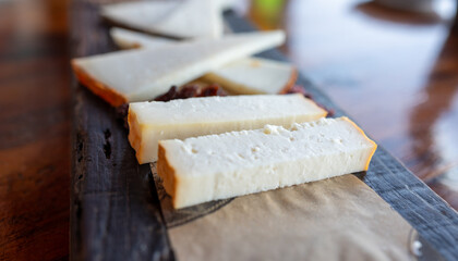 Tasting of Spanish cheeses made on Canary islands, goat cheese, smoked and triangles of manchego curado cheese on wooden plank