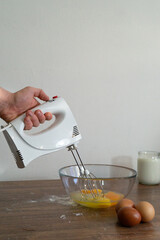 Mixing whisking raw yellow eggs with white mixer. Cooking omelette, pancakes blini with family. Prepare for maslenitsa