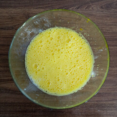 Top view of raw mixed eggs in glass bowl. Close up