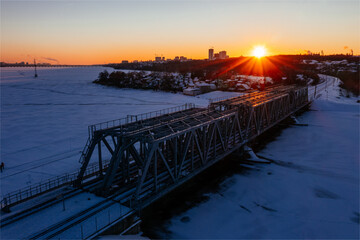 Obraz premium Sunset above railway bridge over frozen Voronezh river in winter