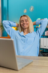 Happy businesswoman freelancer taking break leaning on chair after working celebrating success at...