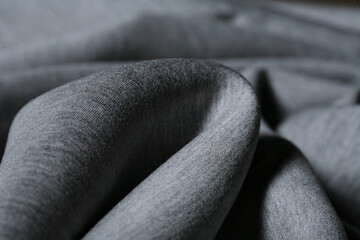 Macro photo of Grey thick neoprene fabric in close up detail. Abstract background wallpaper. Twisted folds cloth. Trendy. Sewing