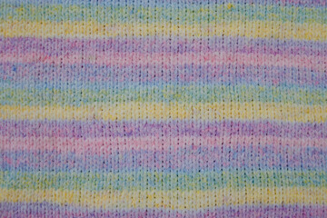Obraz premium knitted fabric with a simple pattern of fluffy melange yarn of lilac, green, yellow, blue colors close-up. Knitting as a form of relaxation and earnings. Beautiful combination of melange shades.