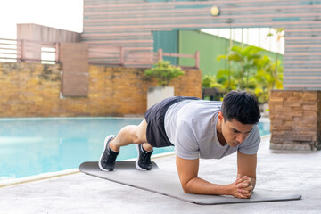 Healthy wellness Asian man sport training fitness plank workout exercise at stadium gym. Young male in sportswear do push-up plank exercise abdominal muscles improve core strength and stability.