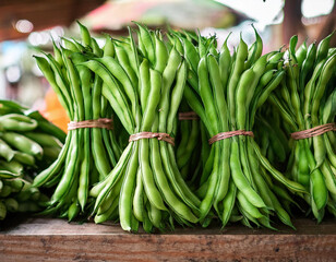 Fototapeta premiumBundles of fresh green beans are neatly stacked at a market stall.