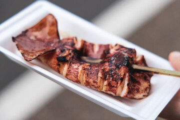 Ikayaki, Grilled roasted Squid with sauce - popular Japanese Street Food, variety of different traditional food snack selection in Tokyo, Japan, street market with local vendor stalls cooking