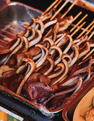 Ikayaki, Grilled roasted Squid with sauce - popular Japanese Street Food, variety of different traditional food snack selection in Tokyo, Japan, street market with local vendor stalls cooking