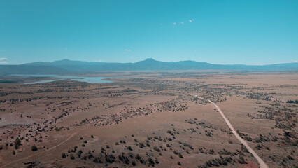 Drone view of a road in a desert environment, cars on the road, lake in the distance