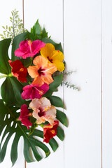 Tropical flowers and leaves on wooden background with copy space, summer vacational background