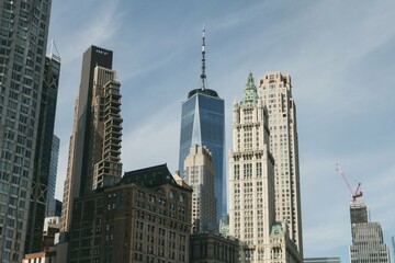 One World Trade Center and surrounding buildings against a blue sky in New York City.