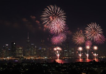 Obraz premium Vibrant fireworks display over city skyline at night with illuminated skyscrapers and reflections