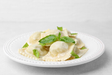 Delicious ravioli with cheese and basil on light table, closeup