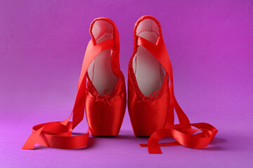 Pair of red pointe shoes on purple background
