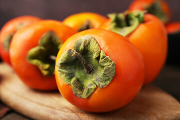 Delicious fresh juicy persimmons on wooden board, closeup