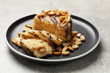 Delicious sweet semolina halva with peanuts on light grey table, closeup