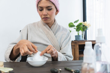 Young Latina woman moisturizing a paper face mask for a skin care treatment