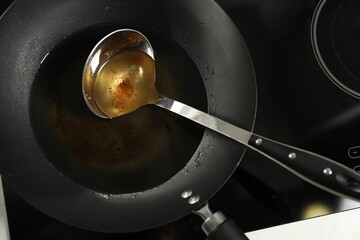Used cooking oil and ladle in frying pan on stove, above view