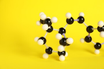 Molecule of retinol (vitamin A) on yellow background, closeup and space for text. Chemical model