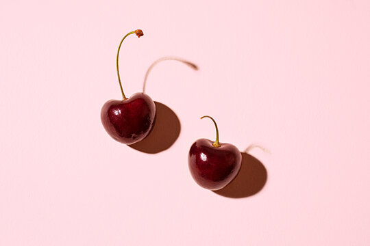 pair of cherries on a pink background